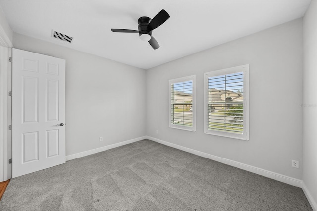 carpeted spare room featuring a ceiling fan, baseboards, and visible vents