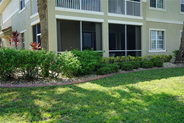 view of side of property with a sunroom and a lawn