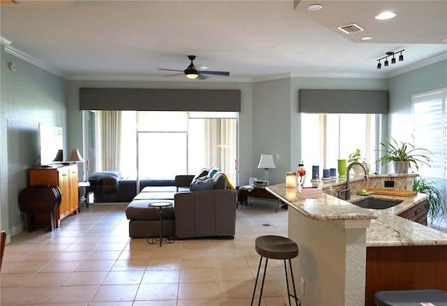 tiled living room featuring rail lighting, crown molding, sink, and ceiling fan