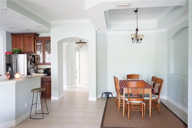 dining area featuring a notable chandelier, a tray ceiling, and crown molding