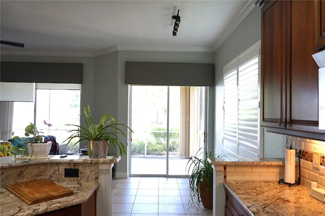 kitchen featuring light stone countertops, decorative backsplash, rail lighting, light tile patterned flooring, and crown molding