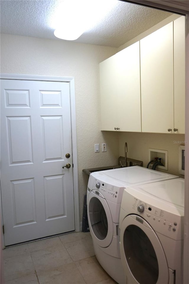 clothes washing area with cabinets, independent washer and dryer, and a textured ceiling