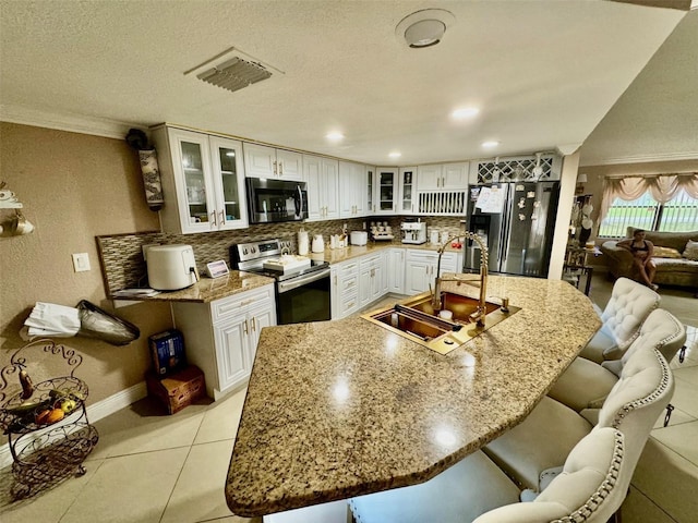 kitchen with stainless steel appliances, white cabinetry, sink, tasteful backsplash, and a breakfast bar