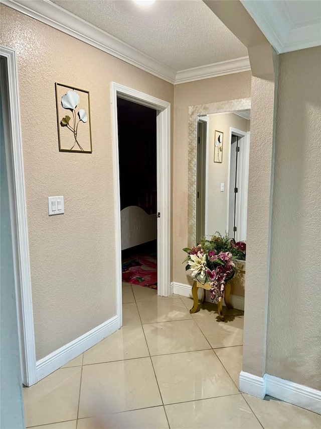 hall with ornamental molding, a textured ceiling, and light tile patterned floors