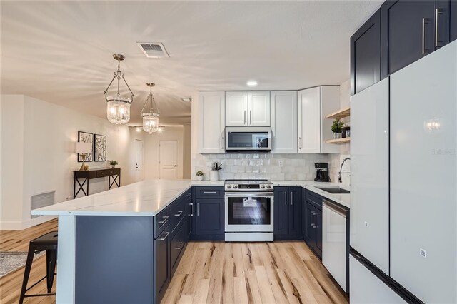 kitchen featuring pendant lighting, a kitchen breakfast bar, light hardwood / wood-style flooring, white cabinetry, and stainless steel appliances