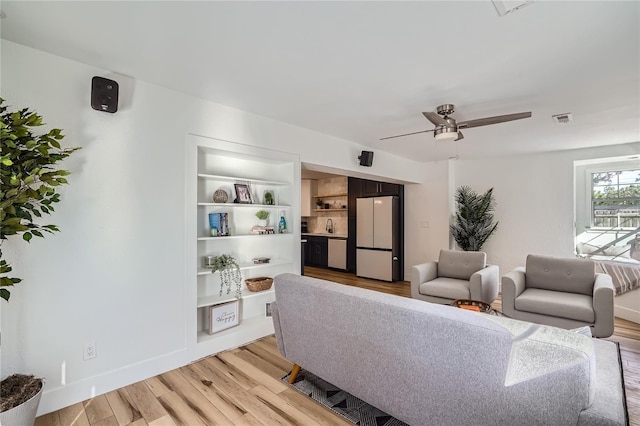 living room featuring ceiling fan, sink, and light hardwood / wood-style floors