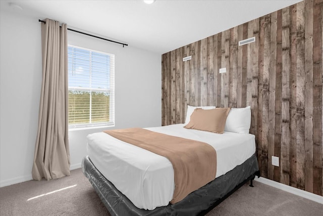 bedroom with carpet floors and wood walls