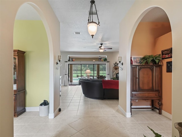 hallway with a textured ceiling and light tile patterned floors