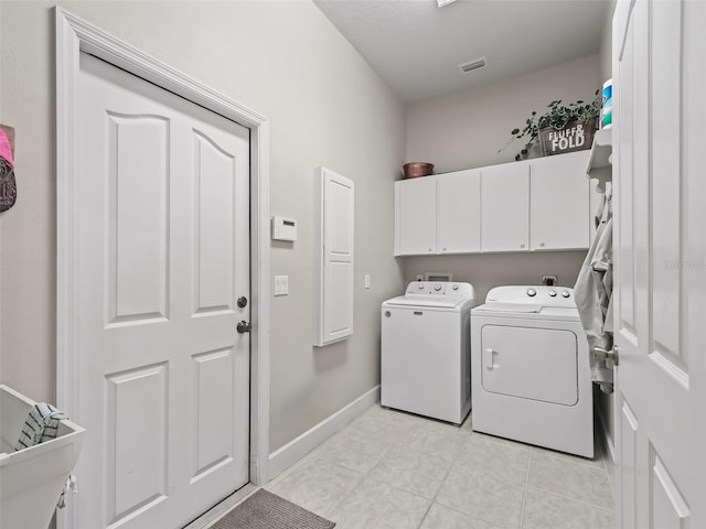 clothes washing area with light tile patterned floors, separate washer and dryer, and cabinets