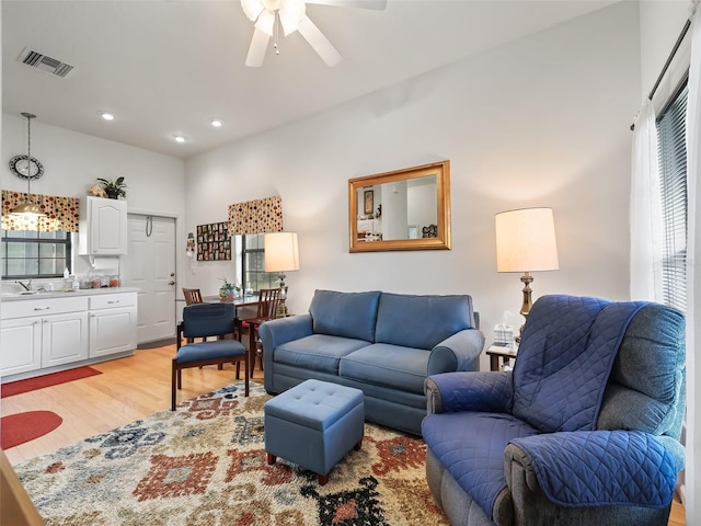 living room featuring light hardwood / wood-style floors, sink, and ceiling fan