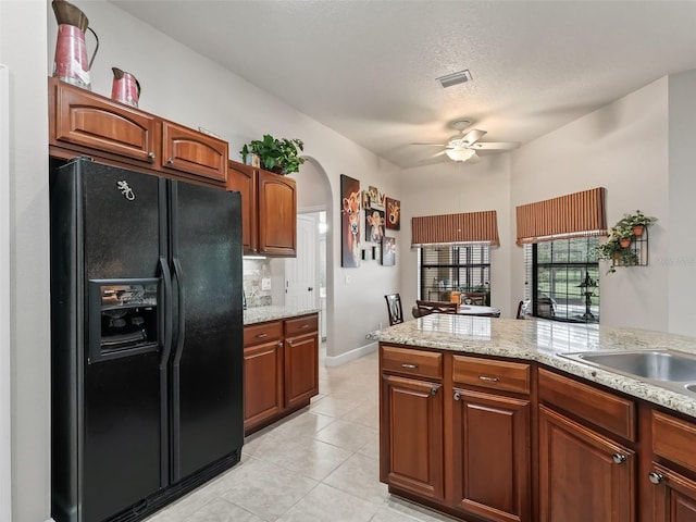 kitchen with ceiling fan, backsplash, black refrigerator with ice dispenser, light stone counters, and light tile patterned flooring