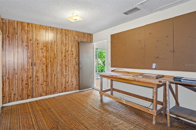 office space featuring a textured ceiling and wooden walls