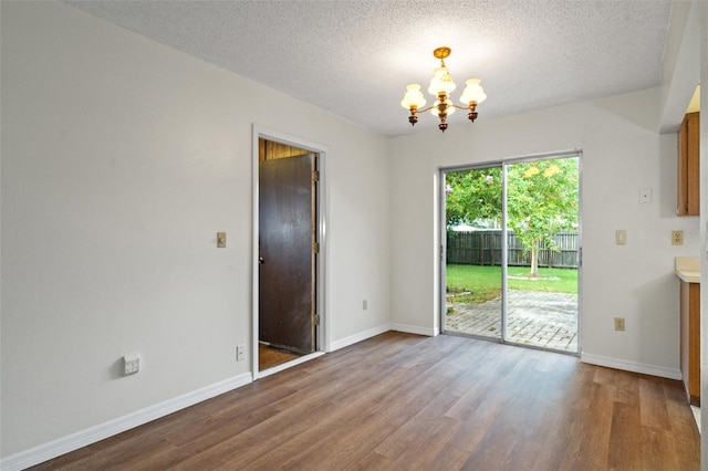 unfurnished dining area with hardwood / wood-style floors, a notable chandelier, and a textured ceiling