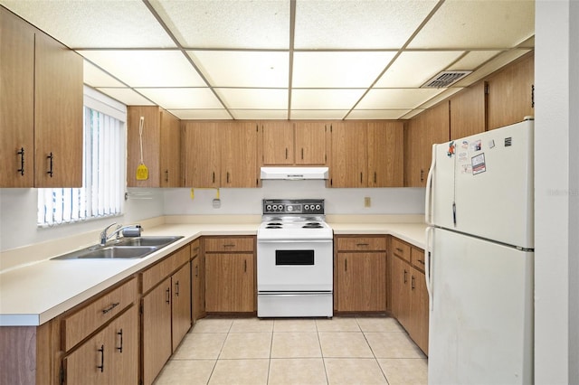 kitchen featuring a paneled ceiling, white appliances, sink, and light tile patterned floors