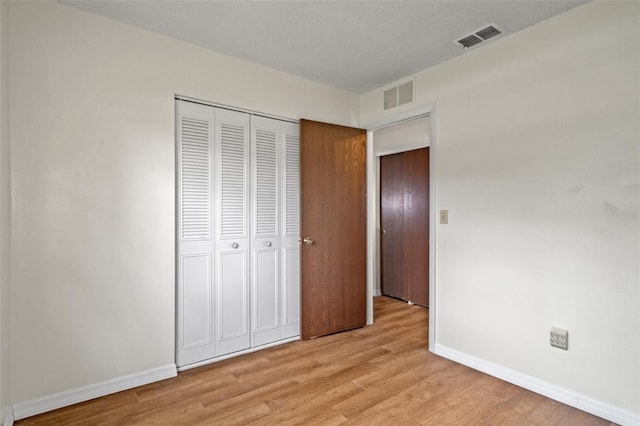 unfurnished bedroom with light hardwood / wood-style flooring and a closet