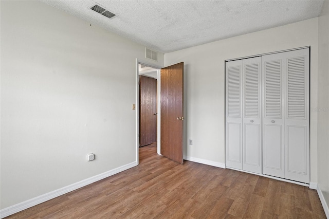 unfurnished bedroom featuring wood-type flooring, a textured ceiling, and a closet