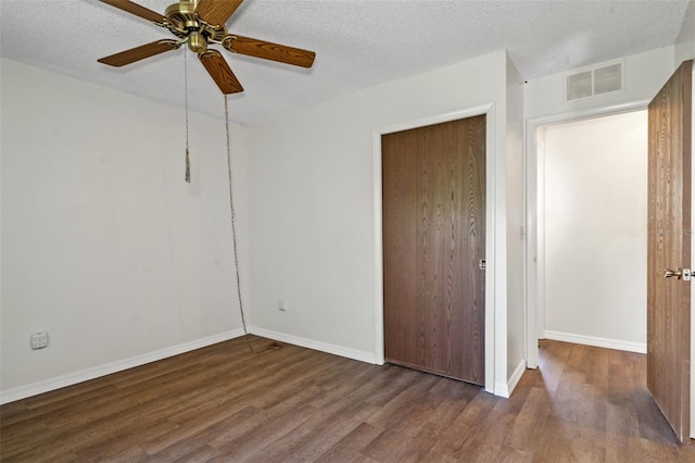 unfurnished bedroom featuring a textured ceiling, dark hardwood / wood-style flooring, a closet, and ceiling fan