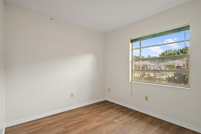 empty room with light hardwood / wood-style floors and a textured ceiling