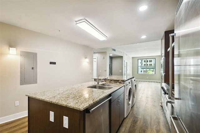 kitchen with dark brown cabinets, stainless steel appliances, an island with sink, sink, and dark hardwood / wood-style floors