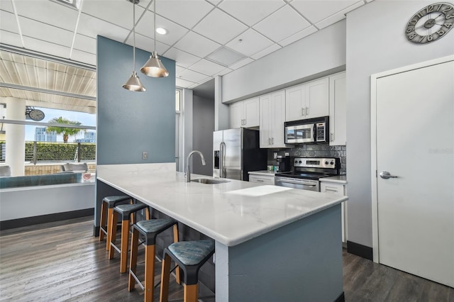 kitchen with backsplash, hanging light fixtures, stainless steel appliances, sink, and white cabinetry