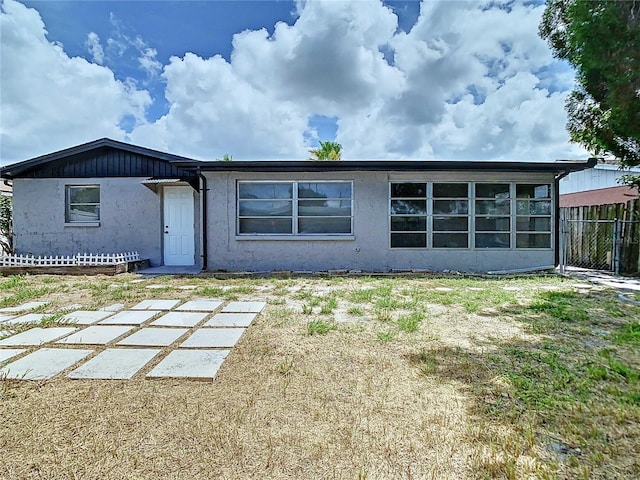 back of house featuring a yard, fence, and stucco siding