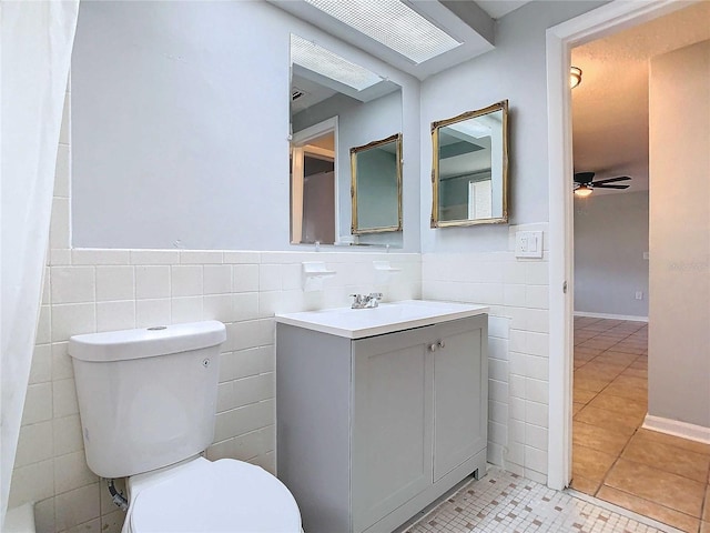 bathroom featuring ceiling fan, toilet, tile patterned floors, and tile walls