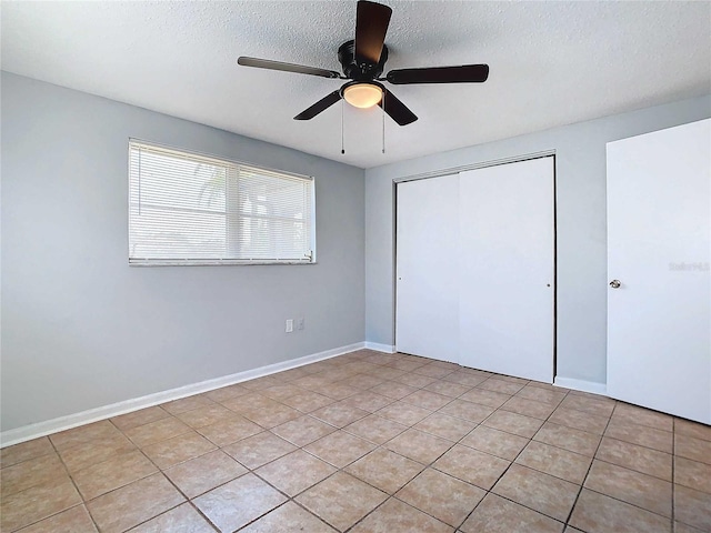 unfurnished bedroom featuring ceiling fan, light tile patterned floors, a closet, and a textured ceiling