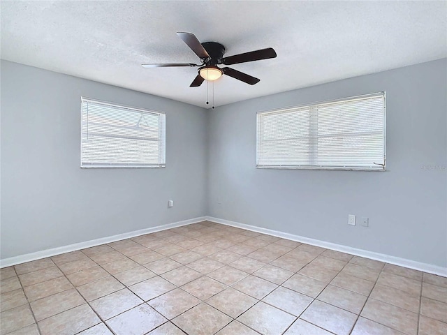 spare room featuring ceiling fan, light tile patterned floors, and a textured ceiling