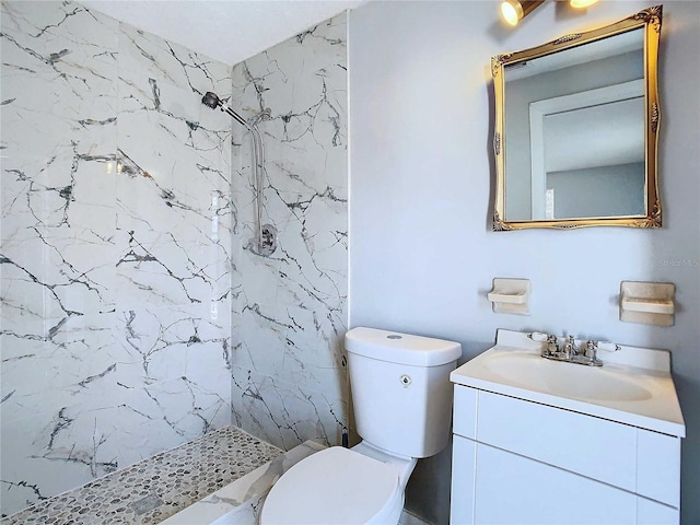 bathroom featuring toilet, a tile shower, and vanity