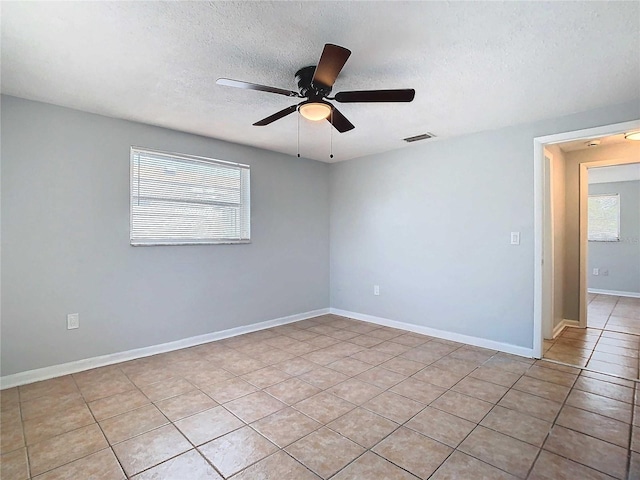 tiled spare room featuring a textured ceiling and ceiling fan