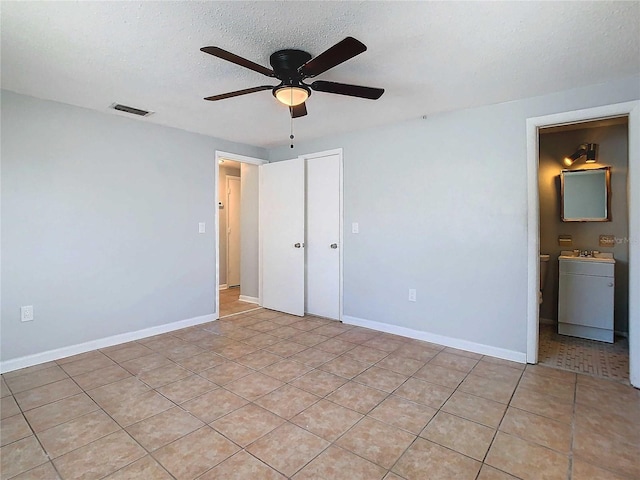 unfurnished bedroom featuring ceiling fan, sink, ensuite bathroom, a textured ceiling, and light tile patterned flooring