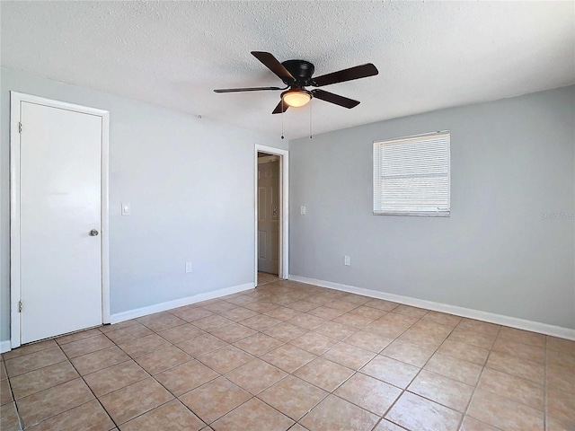 spare room with ceiling fan, a textured ceiling, and light tile patterned floors