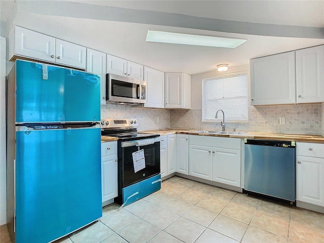 kitchen featuring white cabinetry, appliances with stainless steel finishes, sink, and light tile patterned flooring