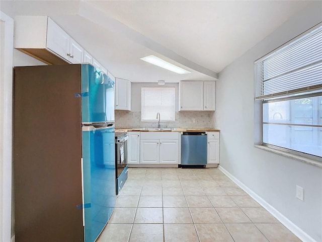 kitchen with decorative backsplash, white cabinets, appliances with stainless steel finishes, light tile patterned floors, and sink