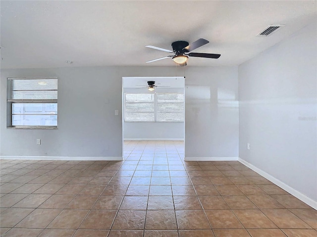 empty room with ceiling fan, a healthy amount of sunlight, and tile patterned floors