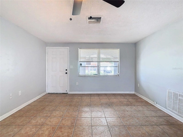 tiled empty room with ceiling fan and a textured ceiling