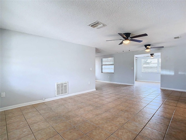 tiled empty room featuring ceiling fan and a textured ceiling