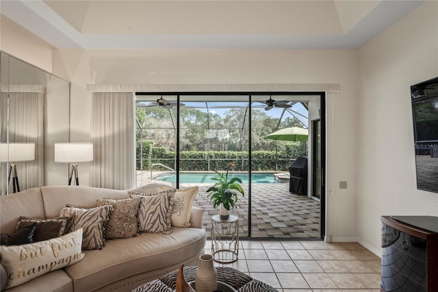 doorway to outside with ceiling fan, plenty of natural light, light tile patterned flooring, and a raised ceiling