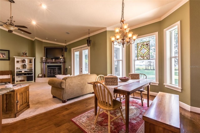 dining area with hardwood / wood-style flooring, ceiling fan with notable chandelier, a tile fireplace, and ornamental molding