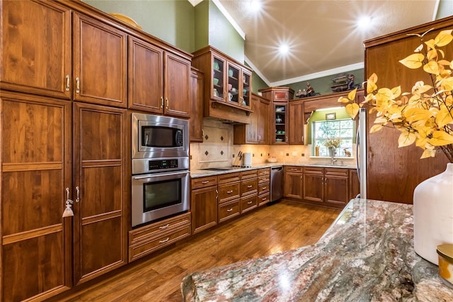 kitchen with backsplash, dark hardwood / wood-style flooring, appliances with stainless steel finishes, stone countertops, and crown molding