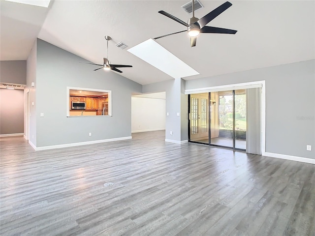 unfurnished living room featuring ceiling fan, vaulted ceiling with skylight, and wood-type flooring