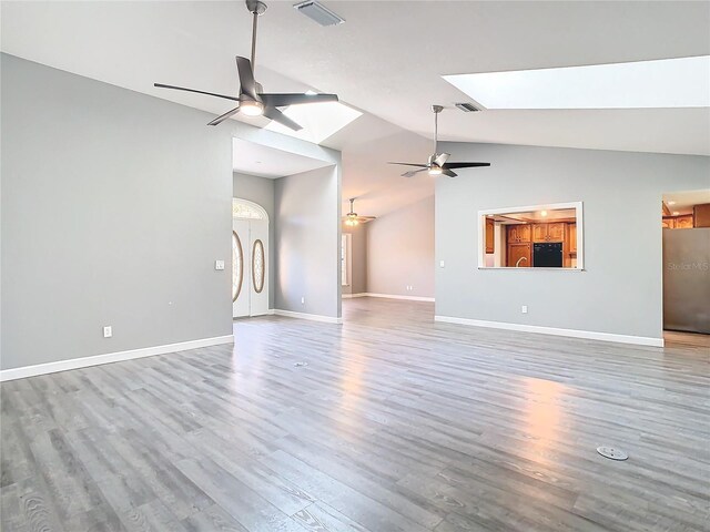 unfurnished living room with ceiling fan, a skylight, and hardwood / wood-style flooring