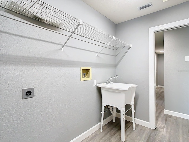 clothes washing area with hardwood / wood-style flooring, washer hookup, and hookup for an electric dryer