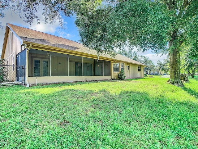 back of property with a sunroom and a yard