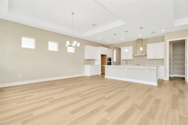 interior space with a tray ceiling, light hardwood / wood-style flooring, and an inviting chandelier