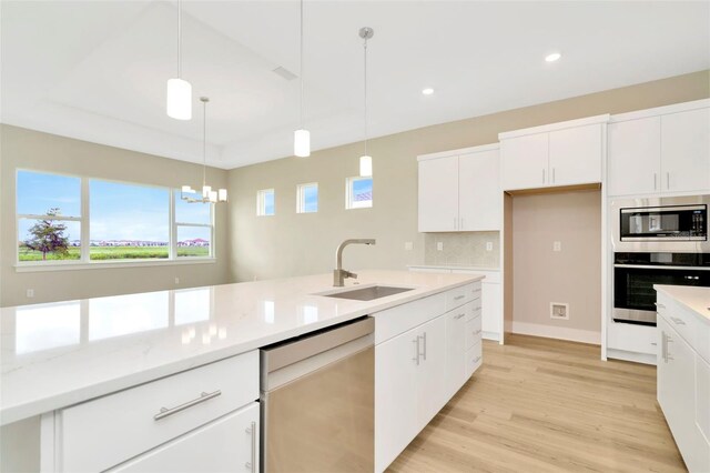 kitchen featuring appliances with stainless steel finishes, decorative light fixtures, light hardwood / wood-style floors, sink, and a notable chandelier