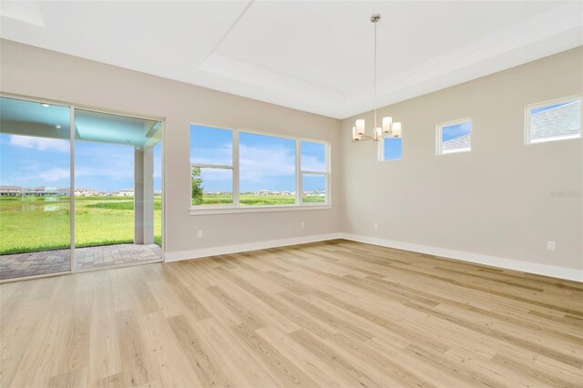 spare room with a notable chandelier and light hardwood / wood-style flooring