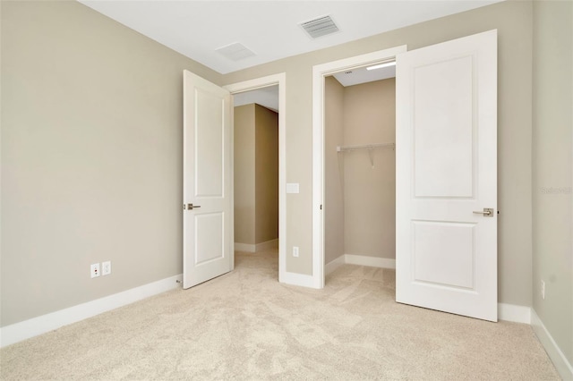 unfurnished bedroom featuring a walk in closet, a closet, and light carpet