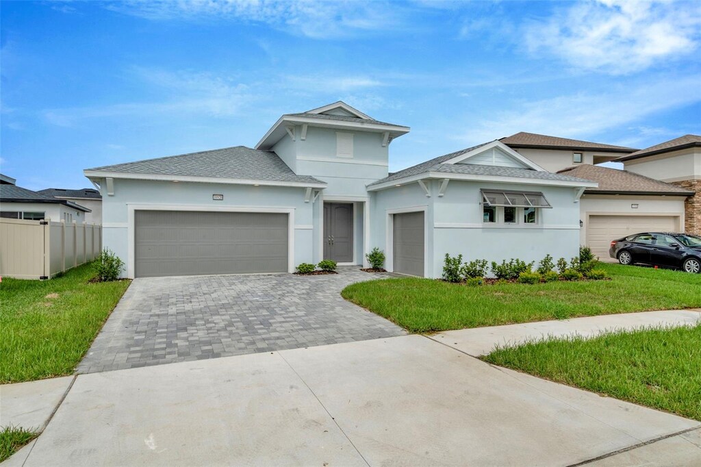 prairie-style house with a garage, decorative driveway, a front yard, and fence