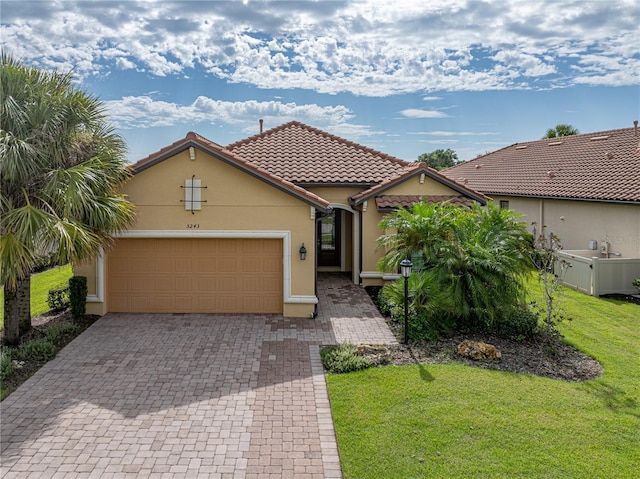 mediterranean / spanish-style house featuring a garage, fence, decorative driveway, a front lawn, and stucco siding